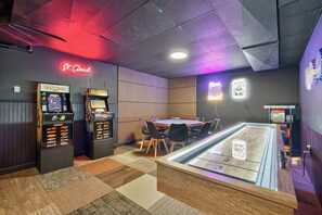 A room with arcade machines, a pool table, and a neon sign reading 'St. Cloud'.