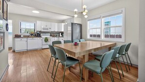 A modern kitchen with white cabinets, a wooden dining table, and teal chairs. - 6 beds / close to SCSU, DT, & Lake George (St. Cloud)