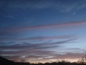 A twilight sky with clouds and a crescent moon.