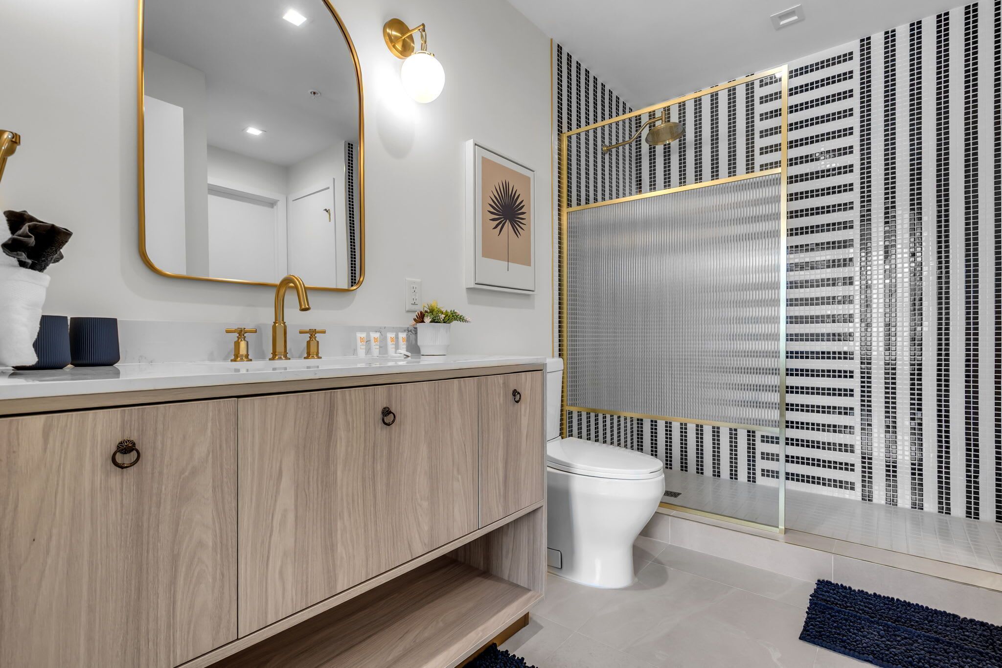 A modern bathroom with a vanity, sink, mirror, and toilet.