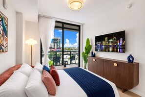 Ein modernes Hotelzimmer mit einem großen Bett, einem Fernseher, einem Balkon mit Blick auf die Stadt und einer Pflanze.