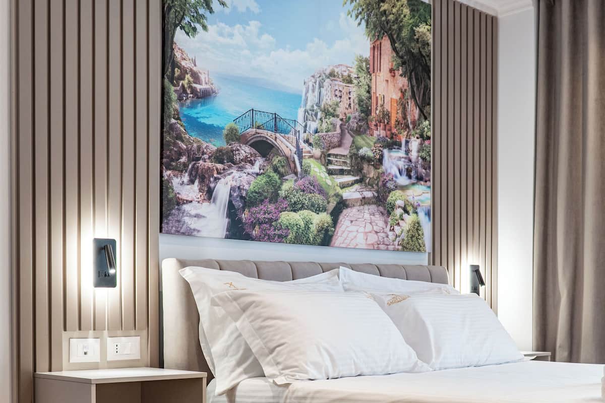 A modern hotel room with a bed, bedside table, and a round coffee table.