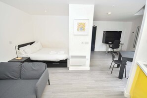 Ein modernes Hotelzimmer mit einem Bett, einer Couch, einem Schreibtisch mit Stuhl und einem Fernseher.