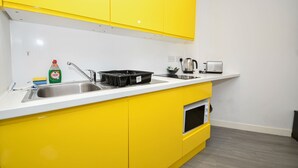 A kitchen with yellow cabinets, a sink, a kettle, and a toaster. - Bright & Contemporary Studio in Sheffield w WiFi (Sheffield)