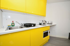 Eine Küche mit gelben Schränken, einem Spülbecken, einem Wasserkocher und einem Toaster.