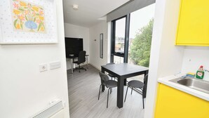 A modern kitchen with a large window, a dining area with a table and chairs, and a framed artwork on the wall. - Bright & Contemporary Studio in Sheffield w WiFi (Sheffield)