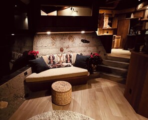A cozy seating area with a sofa, two cushions, a small round table, and a wall with a textured surface.