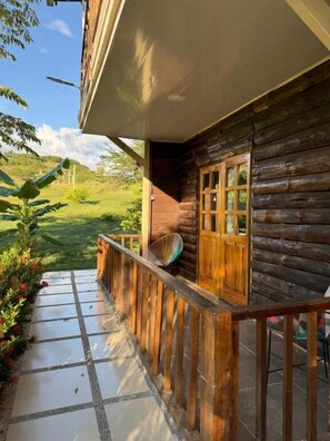 A wooden cabin with a balcony, a window, and a door.