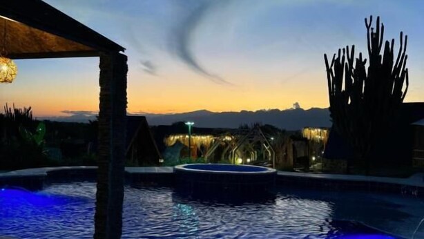 A swimming pool with a stone structure and a cactus in the background. - Hotel Luna Azul Tatacoa  (Villavieja)