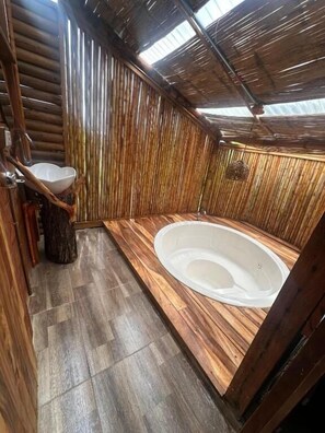 Un interior de madera con una bañera, un lavabo y un tocón de árbol.