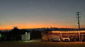 A parking area with several cars and a covered structure with lights.