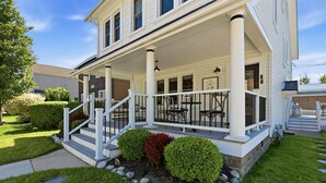 A two-story house with a covered porch, a front yard with a stone pathway, and a small garden with shrubs.