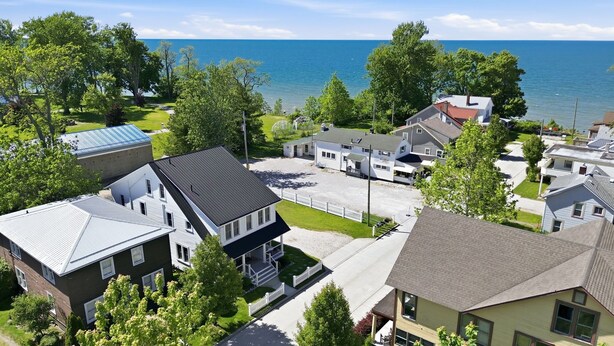 A residential area with houses, a clear view of the sea, and a well-maintained lawn.