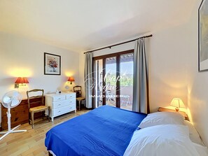 A bedroom with a bed, a dresser, a chair, a fan, and a balcony with curtains. - Mazet T2 for 4 people with balcony in Cavalière (Le Lavandou)