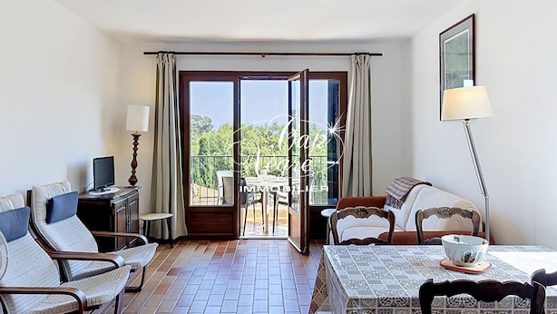 A hotel room with a balcony, a dining table, and a TV. - Mazet T2 for 4 people with balcony in Cavalière (Le Lavandou)