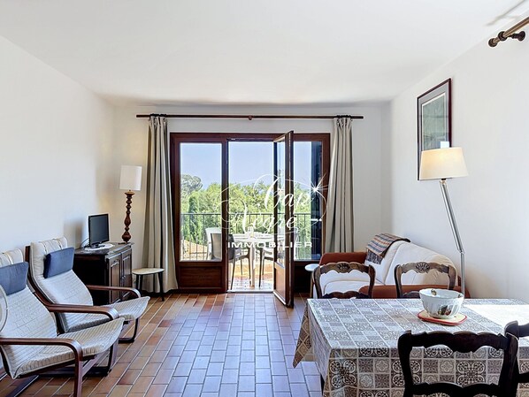 A hotel room with a balcony, a dining table, and a TV. - Mazet T2 for 4 people with balcony in Cavalière (Le Lavandou)