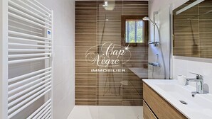 A modern bathroom with a wooden panel wall, a white radiator, a large mirror, and a white sink. - Mazet T2 for 4 people with balcony in Cavalière (Le Lavandou)
