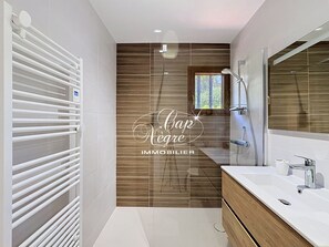 A modern bathroom with a wooden panel wall, a white radiator, a large mirror, and a white sink. - Mazet T2 for 4 people with balcony in Cavalière (Le Lavandou)