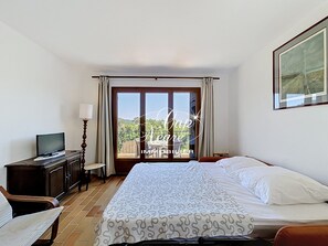A hotel room with a bed, a TV, a desk, and a window with curtains. - Mazet T2 for 4 people with balcony in Cavalière (Le Lavandou)