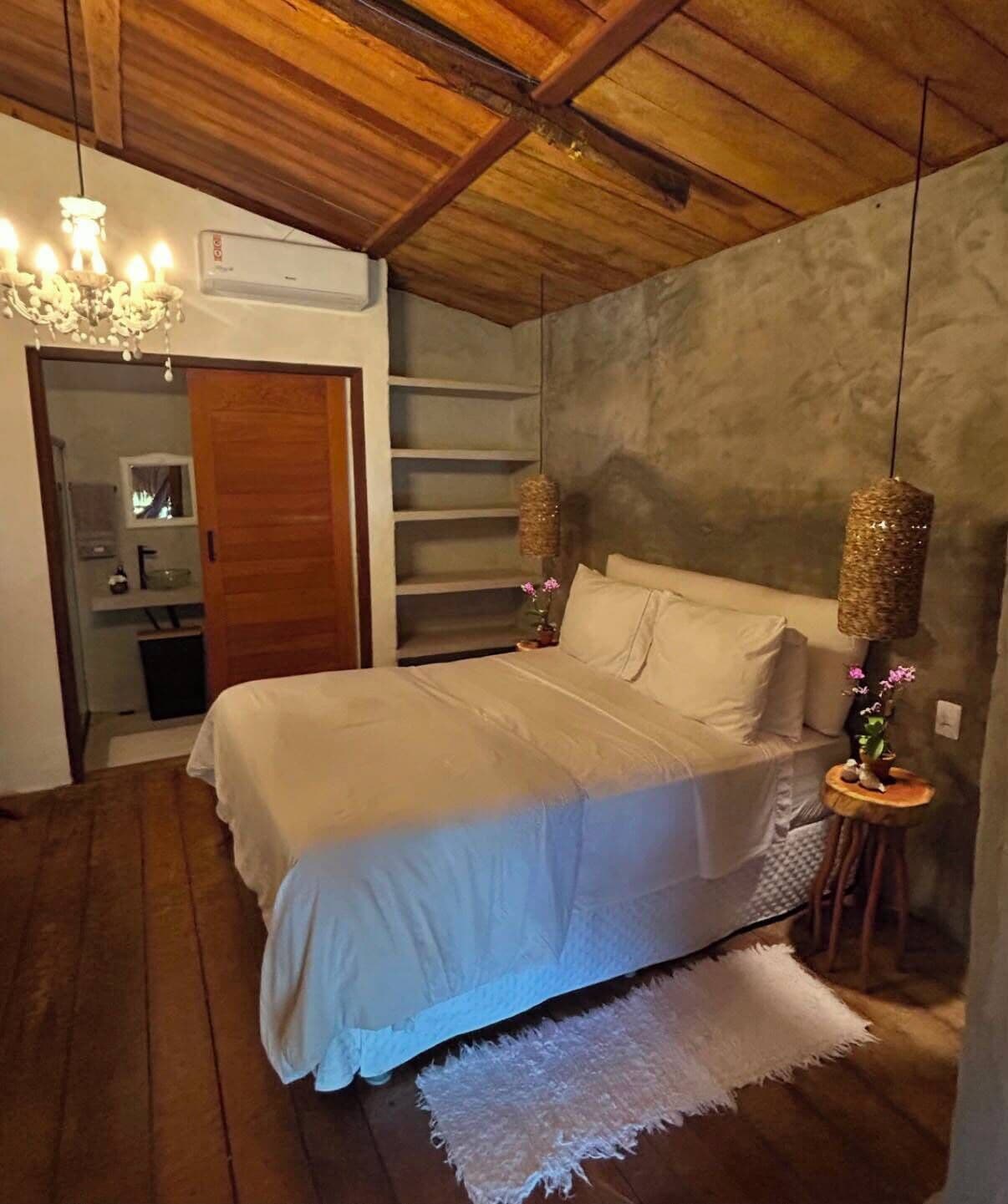 A bedroom with a bed, a chandelier, a hanging lamp, a small table, and a white rug.