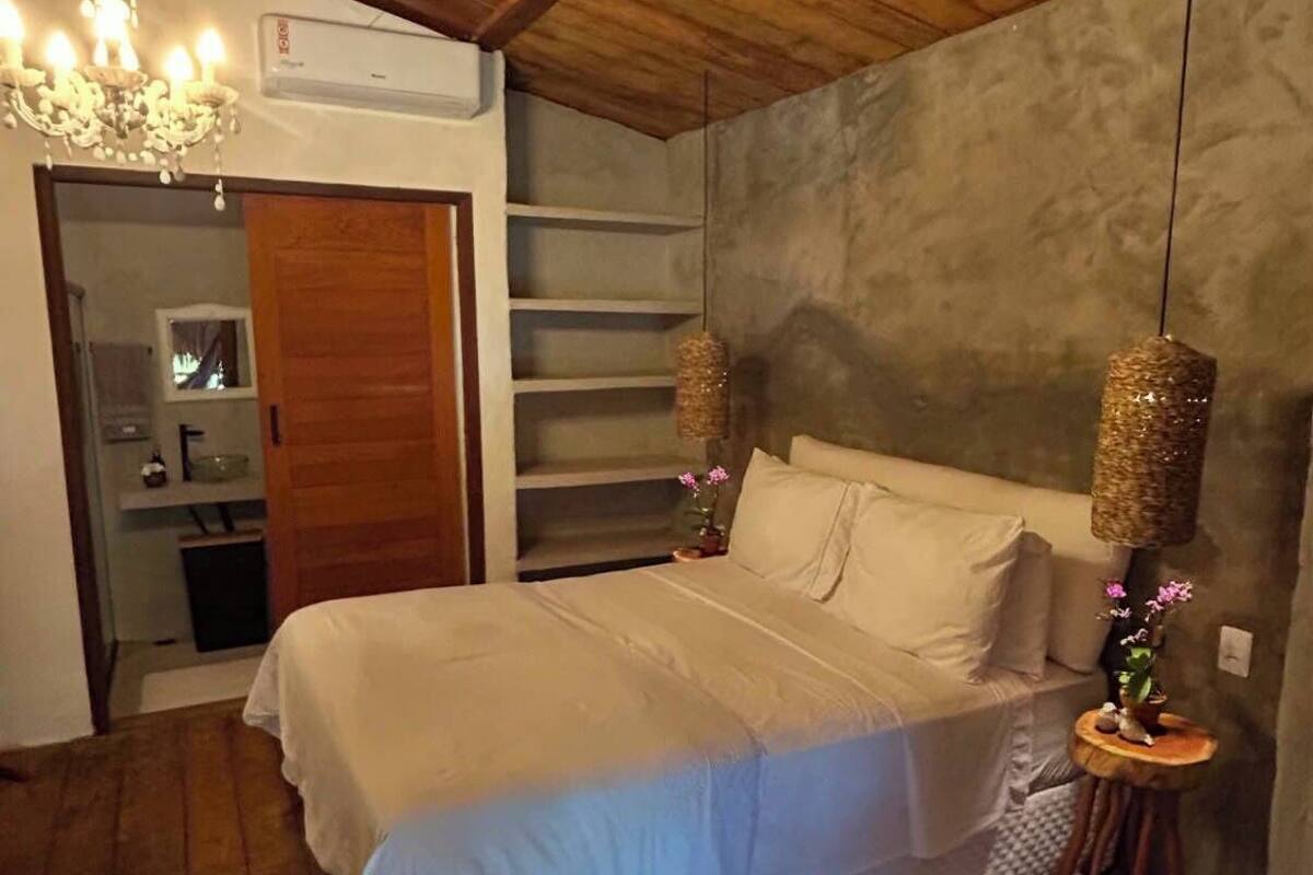A bedroom with a bed, a chandelier, a hanging lamp, a small table, and a white rug.