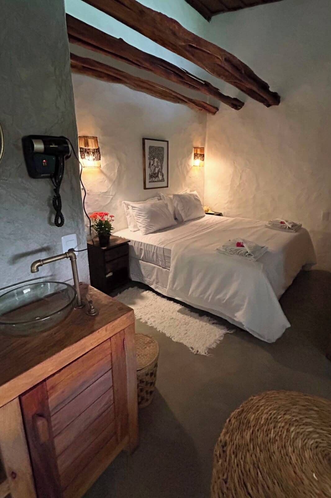 A bedroom with a bed, bedside table, lamp, and a wall-mounted phone.