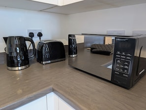 Une cuisine moderne équipée d’un grille-pain, d’une bouilloire et d’un four à micro-ondes.