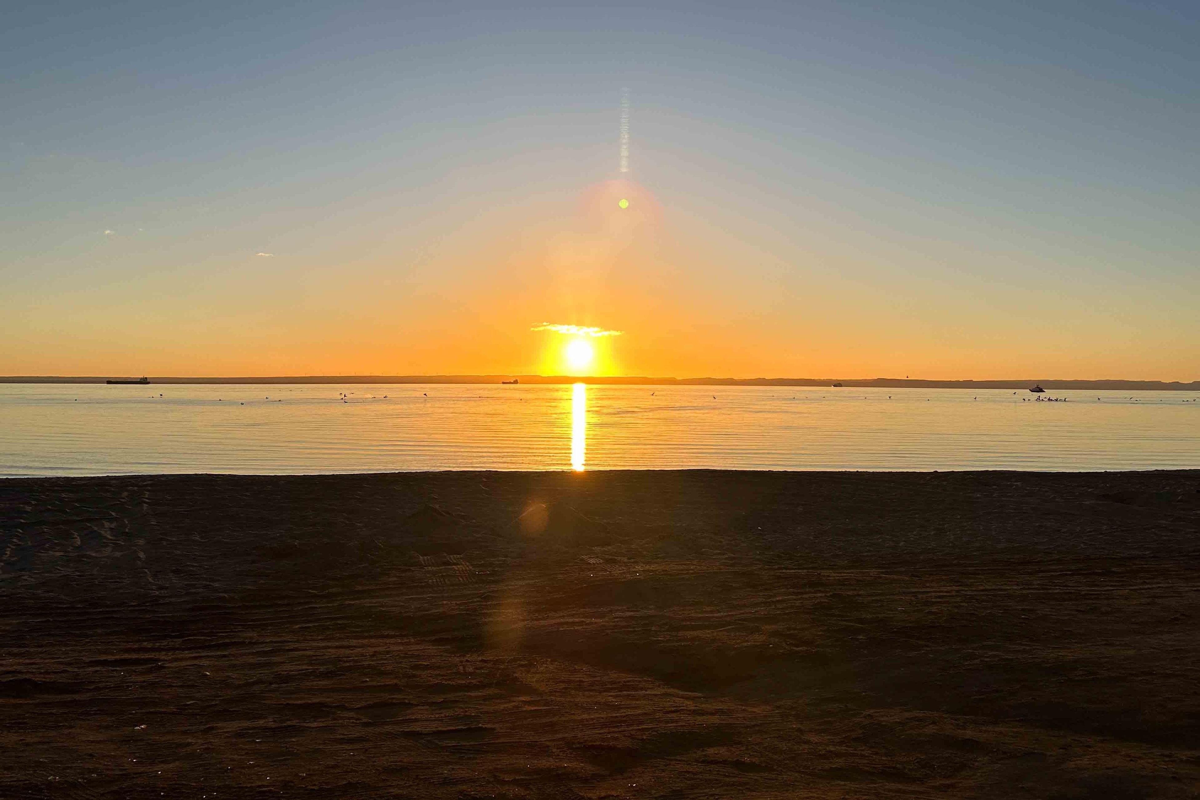 A sunset over a calm body of water with a clear horizon.
