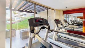 Ein Fitnessstudio mit Laufbändern und Trainingsgeräten, großen Fenstern und Blick auf ein Gebäude.