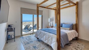 Ein Schlafzimmer mit Himmelbett, einer Schiebetür zu einem Balkon und einem kleinen Nachttisch mit Lampe.