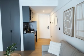 Una cocina moderna con gabinetes grises, una puerta blanca y un área de comedor con un sofá gris y una almohada blanca.