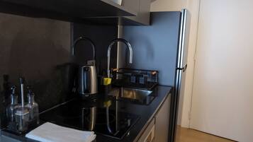 A modern kitchen with a black countertop, stainless steel appliances, and a built-in oven.