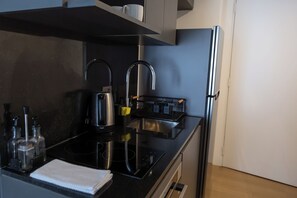 Una cocina moderna con encimera negra, electrodomésticos de acero inoxidable y horno empotrado.
