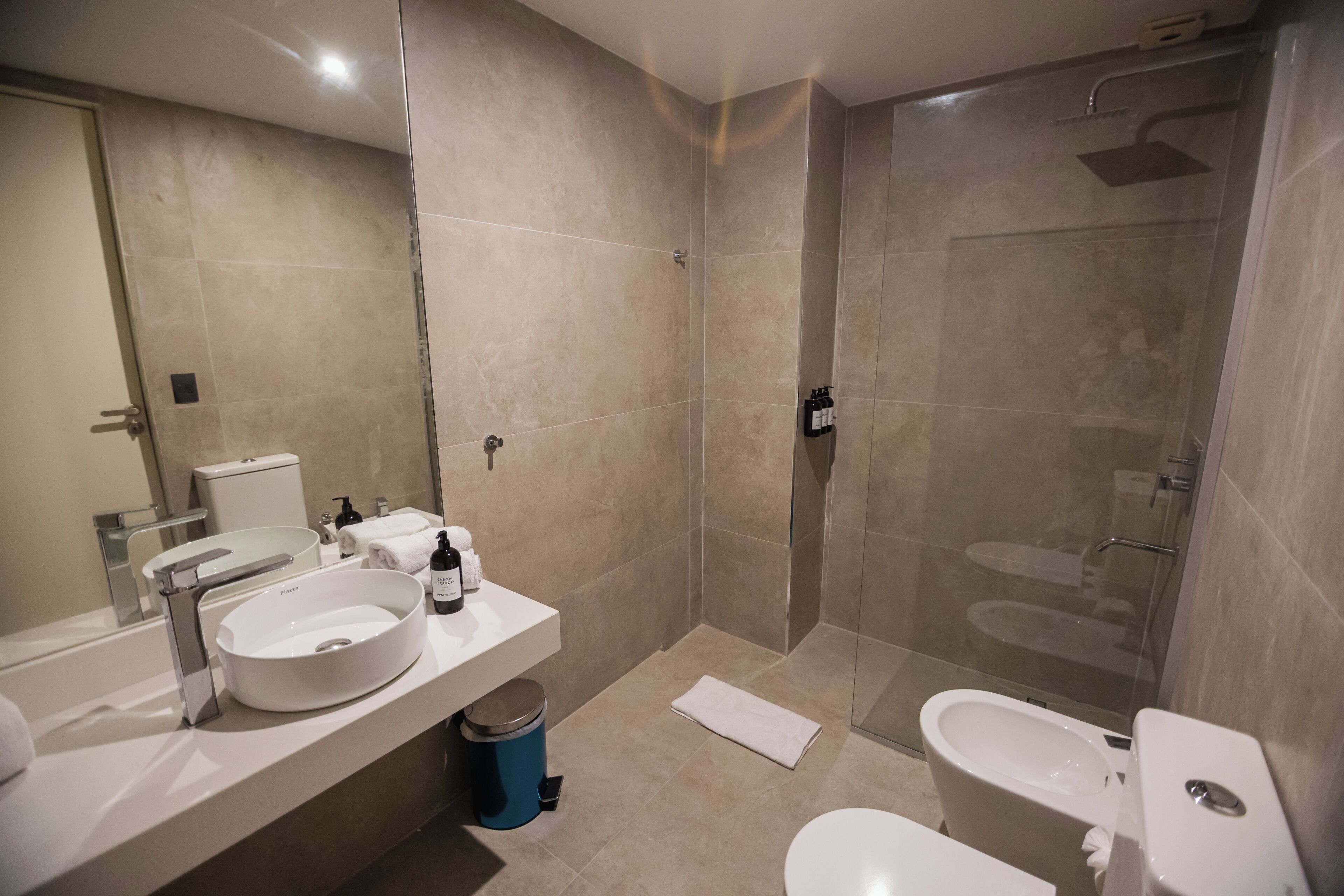 Een moderne badkamer met een grote spiegel, een wastafel, toilet en een douche.
