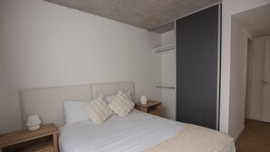 Une chambre à coucher avec un lit, des tables de chevet, une lampe et une armoire.