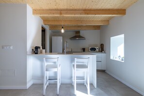 A compact kitchen with a wooden ceiling, a built-in microwave, and a window providing natural light.