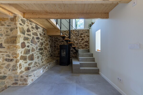 A stone-walled interior with a wooden staircase leading to a loft.