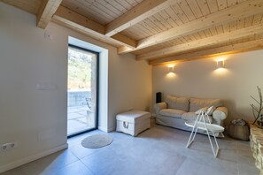 A modern interior with a wooden ceiling, a sofa, a small table, and a view through a glass door.