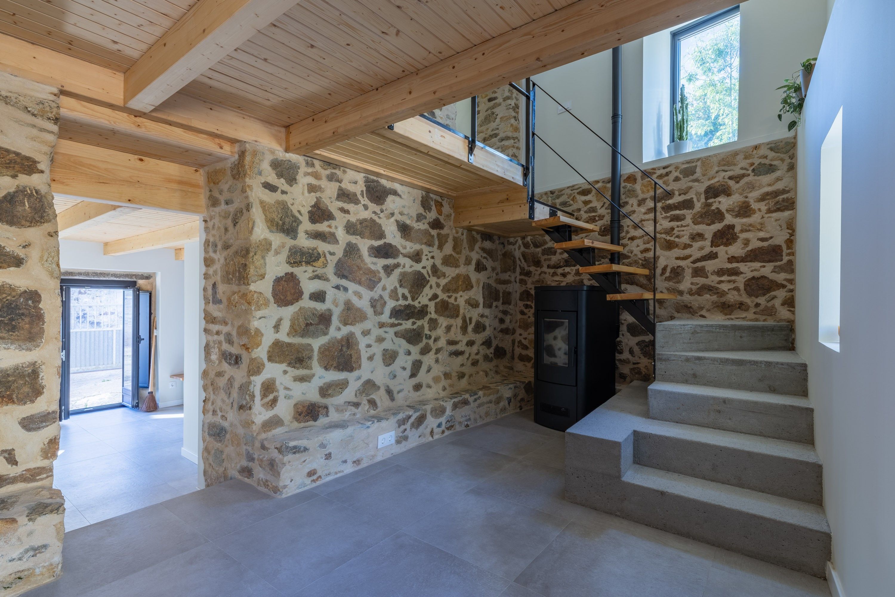 En modern inredning med stenväggar, en trappa och en öppen spis.