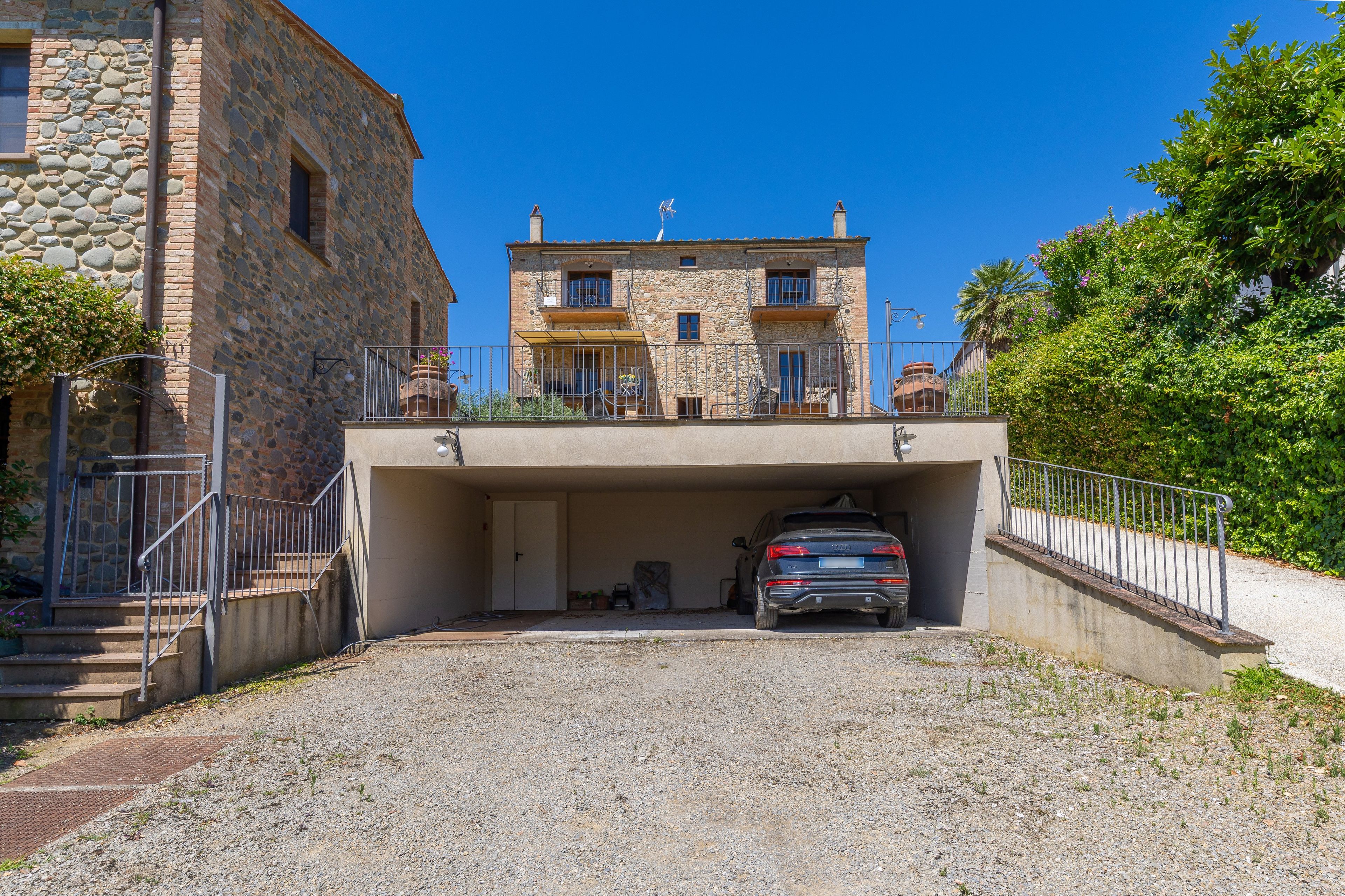 A building with a stone facade, a covered parking area, and a car parked inside.