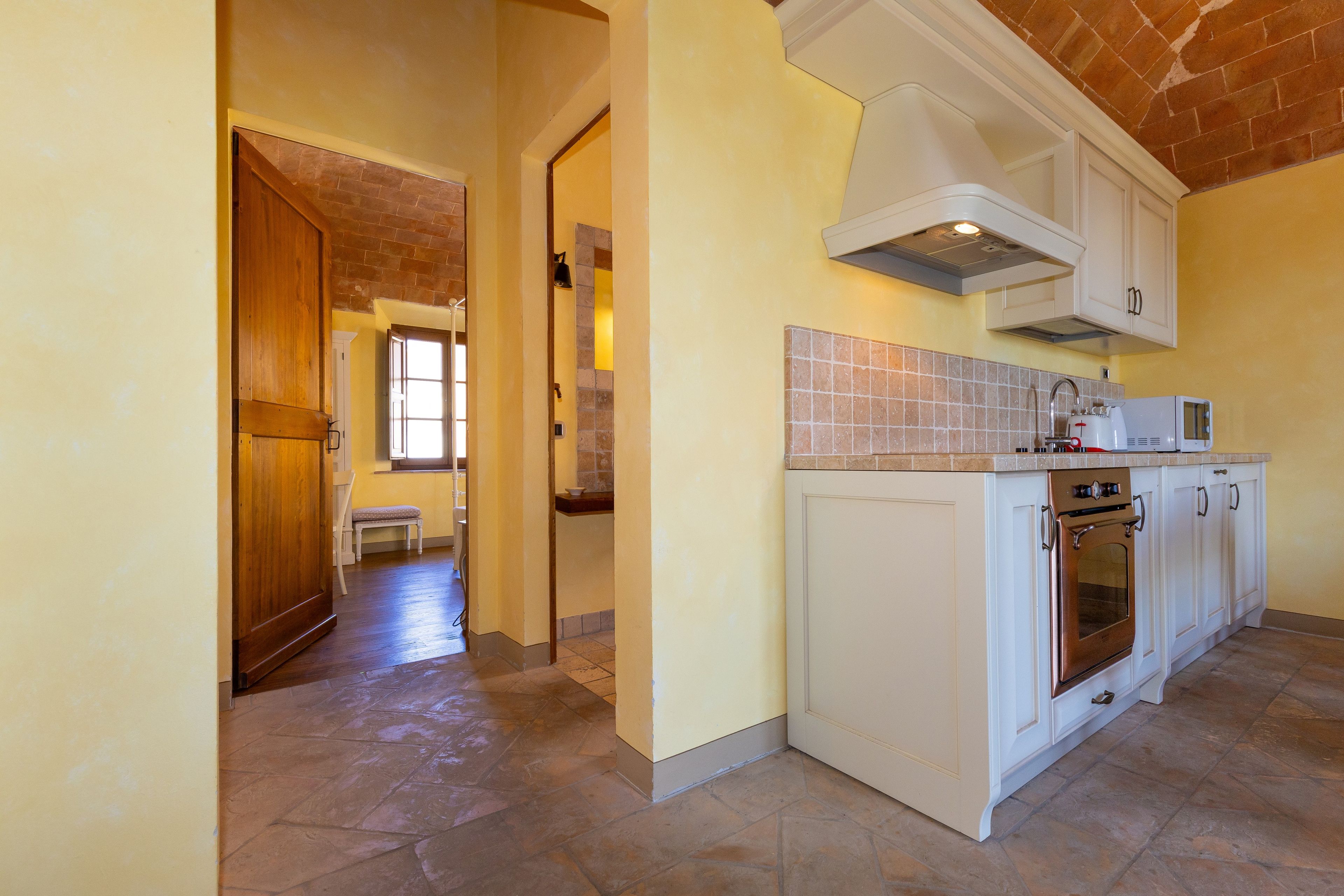 A kitchen with white cabinets, a built-in oven, and a microwave.