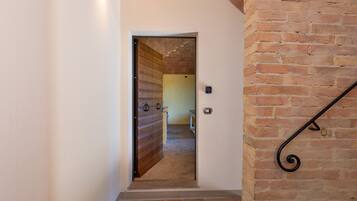 A narrow hallway with a wooden door leading to a room with a tiled floor.