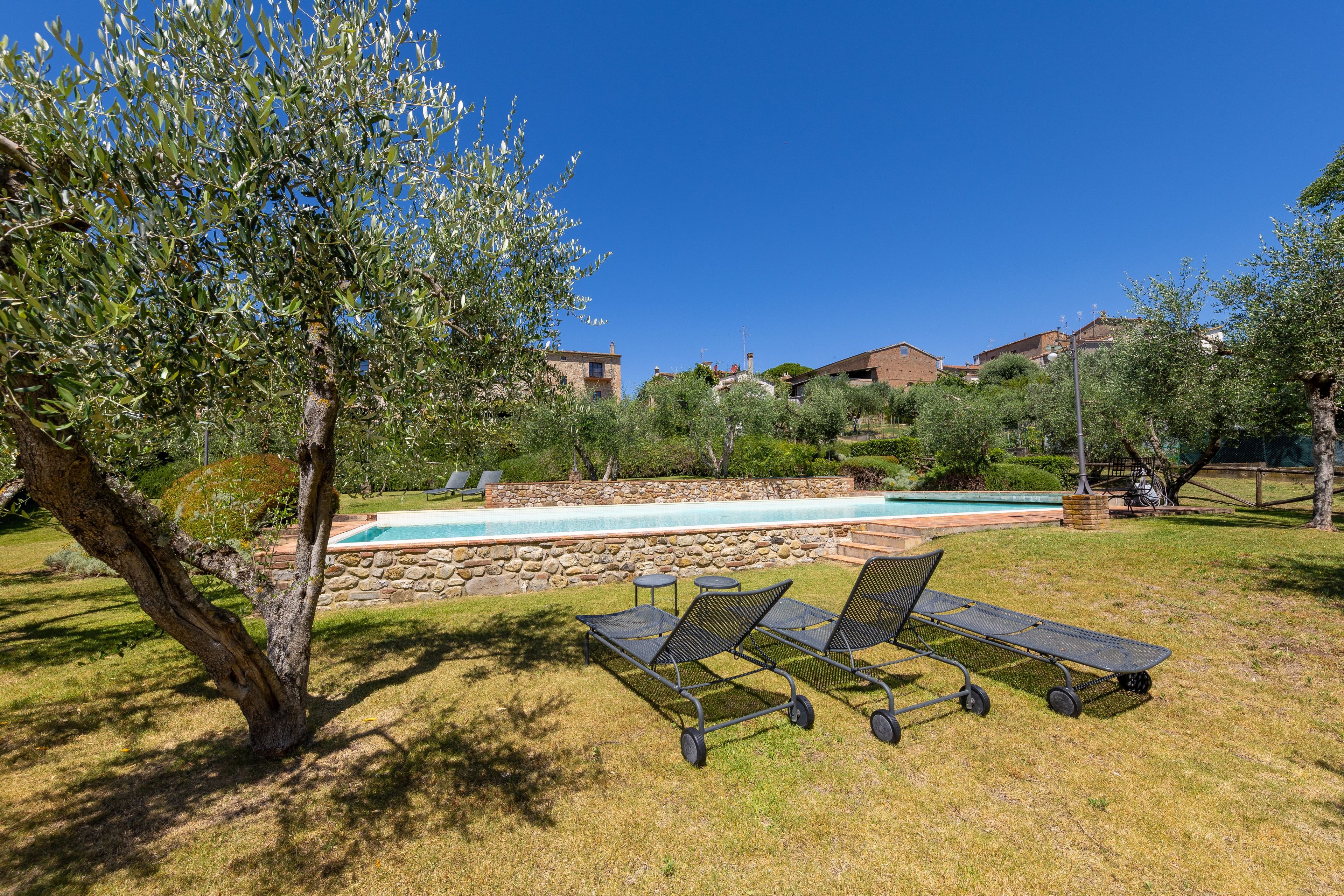 A pool area with lounge chairs and a stone wall.