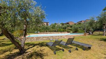 A pool area with lounge chairs and a stone wall.