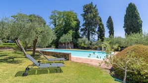 A swimming pool with a grassy area, lounge chairs, and trees. - Apartment 'Rosmarino' with Shared Pool, Garden, and Wi-Fi (Laiatico)