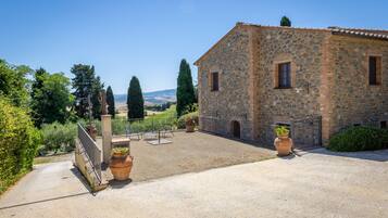 A stone building with a gravel courtyard, a gate, and potted plants.