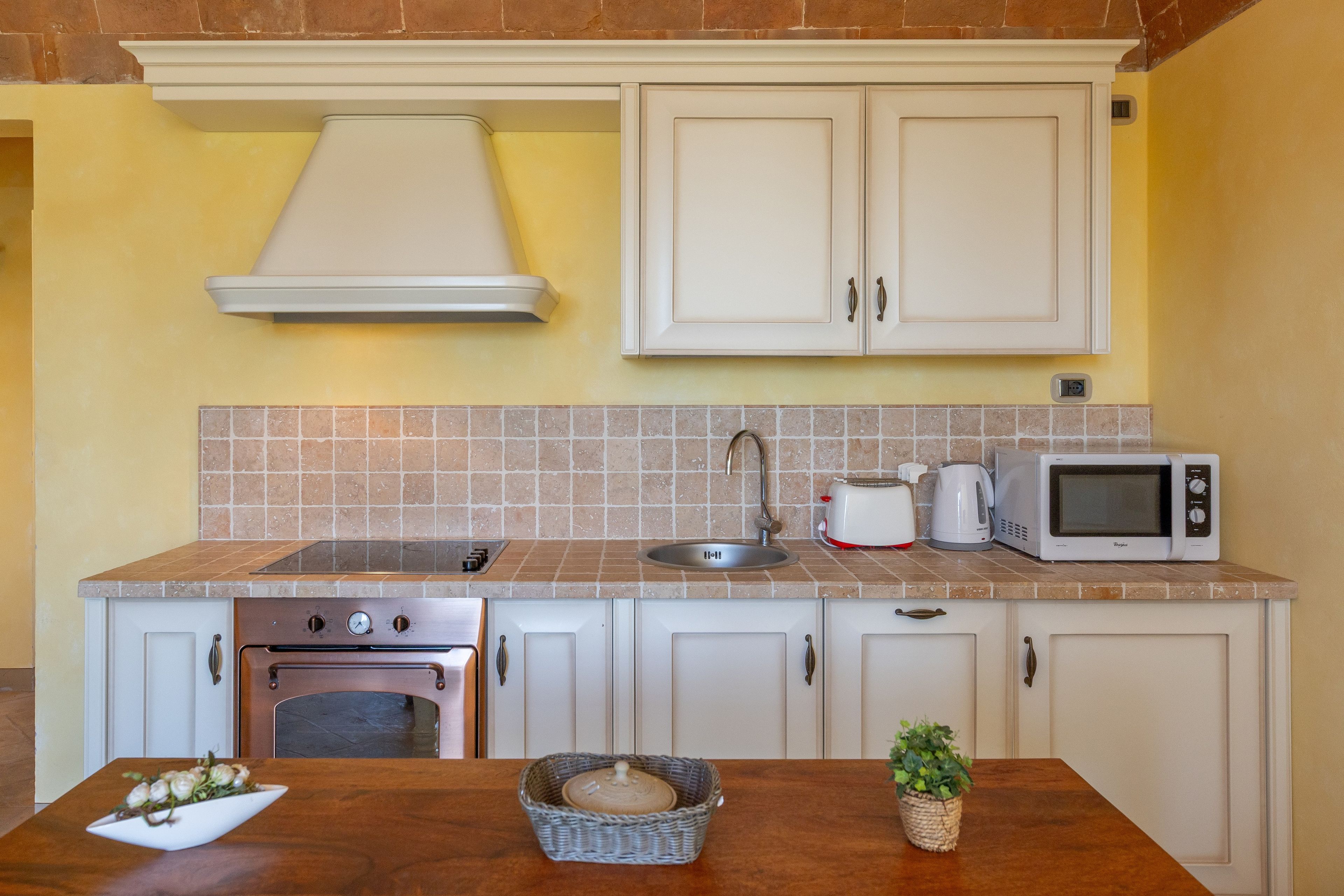 A kitchen with white cabinets, a stove, a microwave, and a sink.
