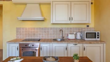 A kitchen with white cabinets, a stove, a microwave, and a sink.