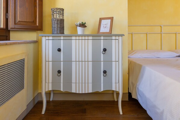A room with a bed, a bedside table with a lamp, and a radiator.