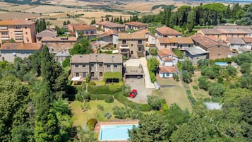 A residential area with stone buildings, a swimming pool, and a red car parked in the yard.